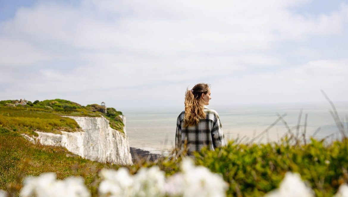 Frau auf den Klippen, im Hintergrund Meer und weiße Klippen von Dover