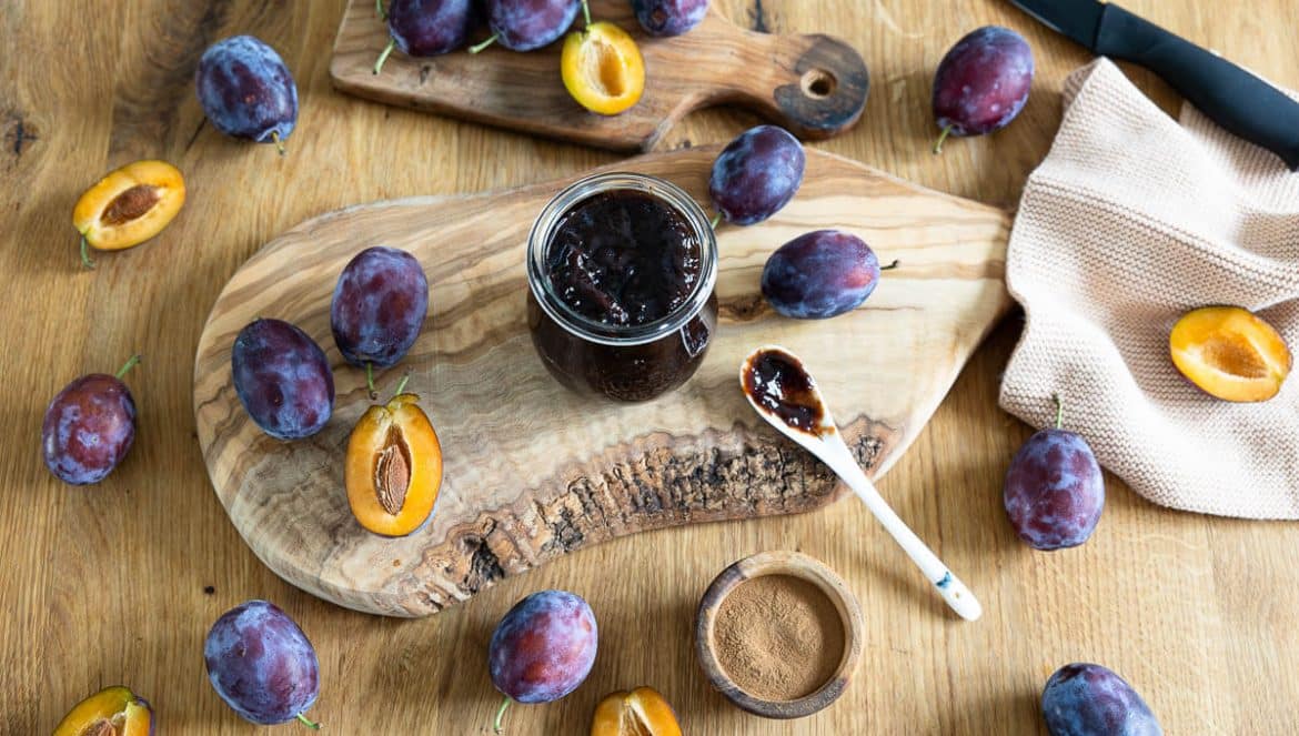Zwetschgenmus: Geöffnetes Weckglas mit Pflaumenmus auf einem Holzbrett