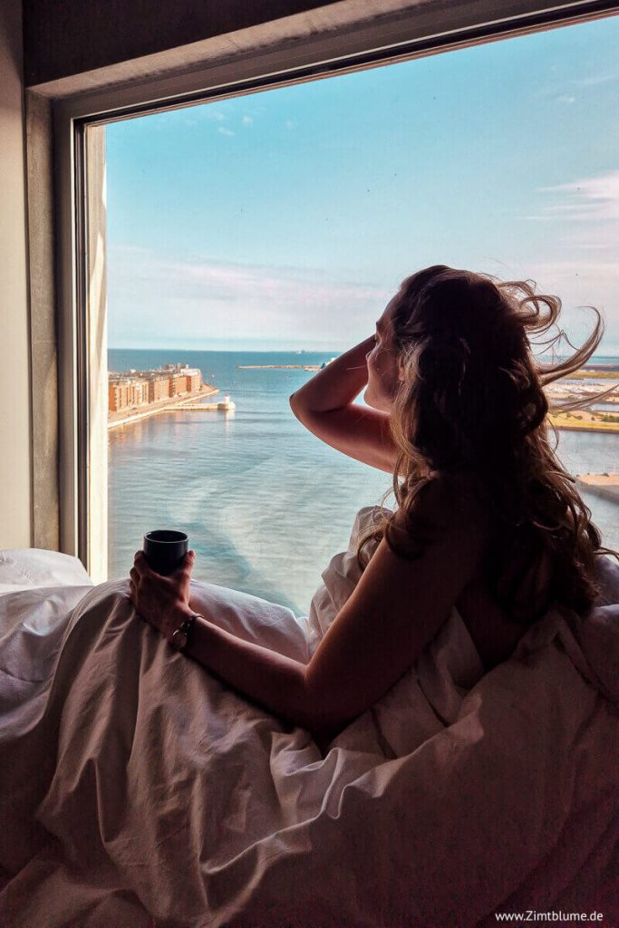Frau am Fenster mit Blick auf den Hafen von Malmö