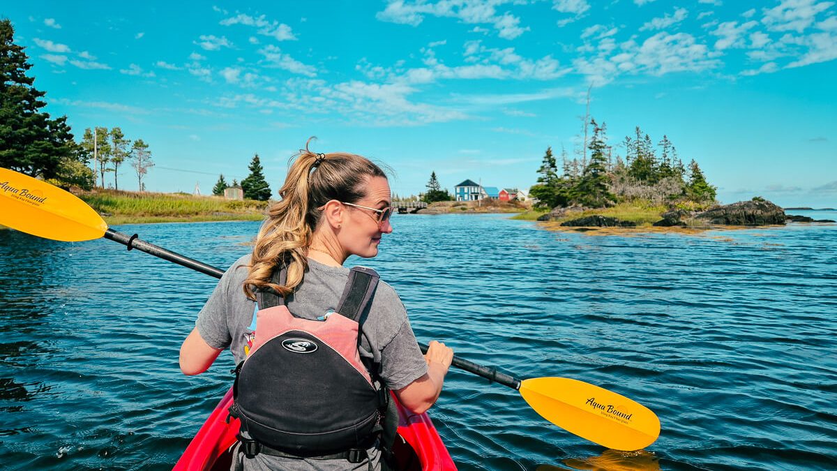 Frau im roten Kajak bei Blue Rocks, Nova Scotia