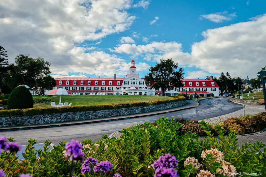 Blumen im Vordergrund, Hotel Tadoussac mit weiß-roter Fassade